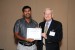 Dr. C. Dale Zinn, IMSCI 2012 Program Committee Chair, giving Mr. Sulaiman Ashraph the best paper award certificate of the session "Disciplinary Research and Development I." The title of the awarded paper is "RPD: Reusable Pseudo-Id Distribution for a Secure and Privacy Preserving VANET."